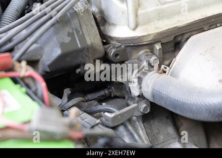 Vista dettagliata delle parti del motore dell'auto, compresi tubi flessibili e cavi, evidenziando gli intricati collegamenti meccanici e componenti. E perdite di gas. Foto Stock