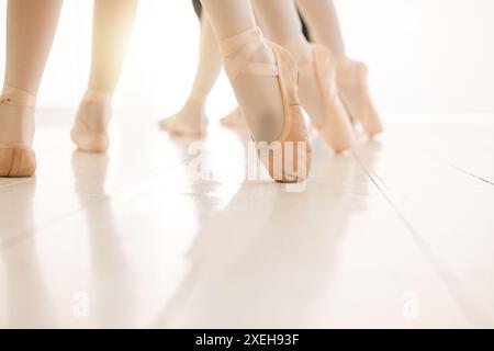Scarpe, gambe e studenti in formazione di balletto e apprendimento con insegnante o istruttore in classe o scuola d'arte. Recital, pavimento o ballerine che ballano Foto Stock