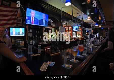 New York, Stati Uniti. 27 giugno 2024. I mecenati siedono al bar di un pub irlandese mentre gli schermi televisivi muti mostrano il dibattito presidenziale del 2024 tra l'ex presidente degli Stati Uniti Donald Trump e il presunto candidato repubblicano e l'attuale presidente democratico degli Stati Uniti Joe Biden, nel Queens borough di New York City, NY, 27 giugno 2024. (Foto di Anthony Behar/Sipa USA) credito: SIPA USA/Alamy Live News Foto Stock