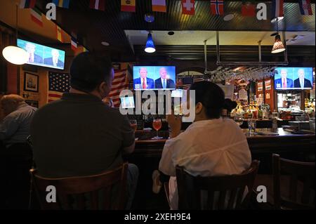 New York, Stati Uniti. 27 giugno 2024. I mecenati siedono al bar di un pub irlandese mentre gli schermi televisivi muti mostrano il dibattito presidenziale del 2024 tra l'ex presidente degli Stati Uniti Donald Trump e il presunto candidato repubblicano e l'attuale presidente democratico degli Stati Uniti Joe Biden, nel Queens borough di New York City, NY, 27 giugno 2024. (Foto di Anthony Behar/Sipa USA) credito: SIPA USA/Alamy Live News Foto Stock