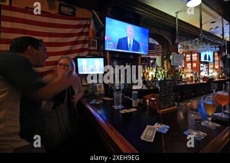 New York, Stati Uniti. 27 giugno 2024. I mecenati siedono al bar di un pub irlandese mentre gli schermi televisivi muti mostrano il dibattito presidenziale del 2024 tra l'ex presidente degli Stati Uniti Donald Trump e il presunto candidato repubblicano e l'attuale presidente democratico degli Stati Uniti Joe Biden, nel Queens borough di New York City, NY, 27 giugno 2024. (Foto di Anthony Behar/Sipa USA) credito: SIPA USA/Alamy Live News Foto Stock