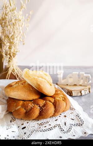 Diversi tipi di pane - kalacha, hala - pane intrecciato con sale grossolano. Pane sul tavolo con bollitore e caraffa, preparato per il consumo. Assortimento di Foto Stock