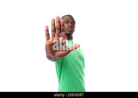 Ritratto di un giovane intelligente uomo africano vestito con t-shirt verde e jeans isolati su sfondo bianco Foto Stock