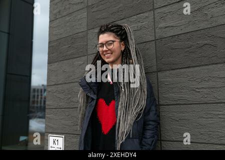 Una donna urbana affascinante con un'acconciatura da dreadlocks sembra informale e inusuale Foto Stock