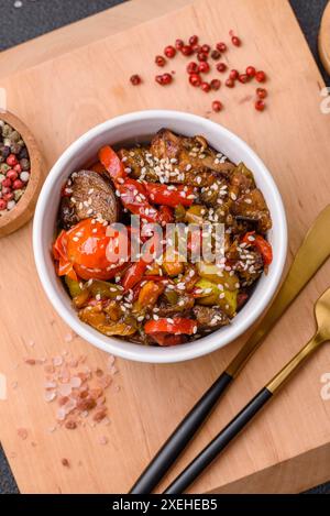 Insalata calda con vitello, pomodori, peperoni, zucchine, sesamo, sale, spezie ed erbe aromatiche Foto Stock