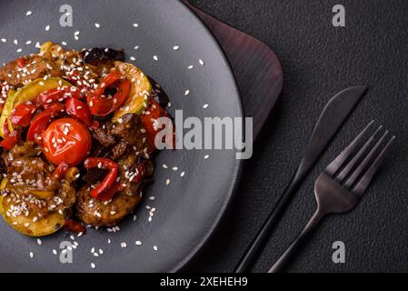 Insalata calda con vitello, pomodori, peperoni, zucchine, sesamo, sale, spezie ed erbe aromatiche Foto Stock