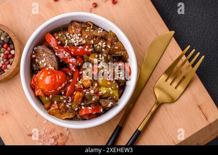 Insalata calda con vitello, pomodori, peperoni, zucchine, sesamo, sale, spezie ed erbe aromatiche Foto Stock