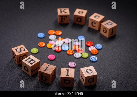 Un concetto che consiste nell'iscrizione della parola sorriso, con emoticon rotonde su uno sfondo di cemento scuro Foto Stock