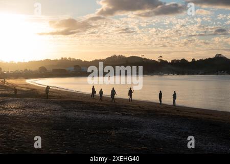 Persone che camminano al tramonto sulla spiaggia di te ti Bay a Waitangi, Bay of Islands, nuova Zelanda Foto Stock