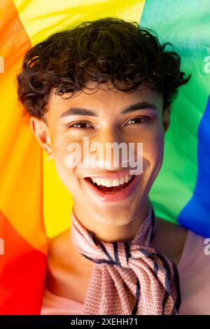 Giovane sorridente con bandiera arcobaleno che celebra l'orgoglio e la diversità LGBTQ+ Foto Stock