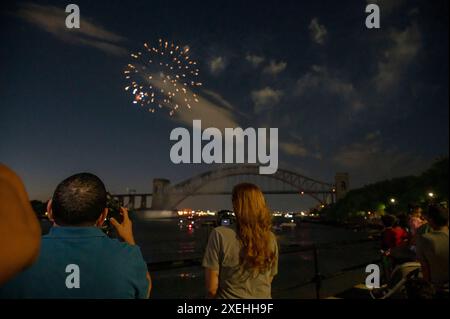 New York, Stati Uniti. 27 giugno 2024. Gli spettatori fotografano i fuochi d'artificio che esplodono durante le celebrazioni annuali dell'Independence Day Celebrations di Central Astoria Park, nel quartiere Queens di New York City. Credito: SOPA Images Limited/Alamy Live News Foto Stock