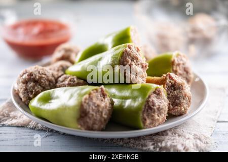 Peperoni verdi ripieni su un piatto pronto per la cottura o la cottura. Foto Stock