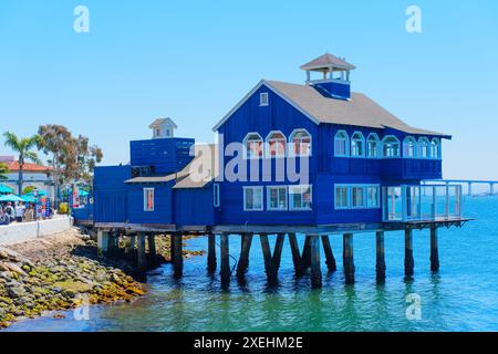 San Diego, California - 16 aprile 2024: Casa blu su palafitte Cafe sull'acqua con cielo limpido sullo sfondo nel Seaport Village di San Diego. Foto Stock