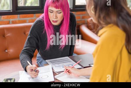 Uomo transgender LGBTQ+ bellissimo e autentico SpecialistÂ con capelli rosa e trans non binari che lavorano insieme Working Design in cr Foto Stock