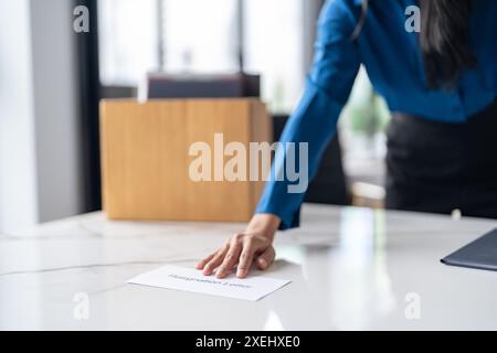 Donna d'affari che invia lettere di dimissioni e che fa le valigie rassegna la stampa o porta con sé una scatola di cartone da ufficio in ufficio. Foto Stock