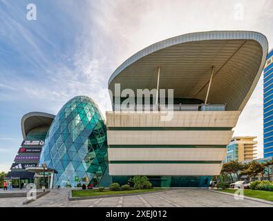 Baku, Azerbaigian - 10 maggio 2024: Poche persone camminano vicino al design moderno del centro commerciale Park Bulvar, in una giornata di sole, con cieli azzurri Foto Stock