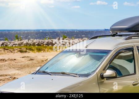 Superficie protettiva riflettente sotto il parabrezza della cicatrice del passeggero parcheggiata in una giornata calda, riscaldata dai raggi del sole all'interno sulla spiaggia costiera marina Foto Stock