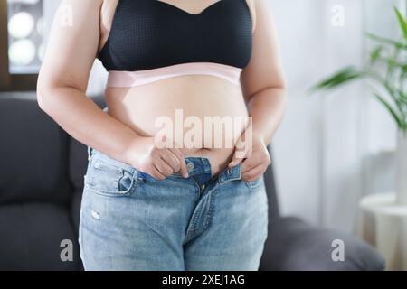 Donna obesa con grasso agitato per la pancia. Donna in sovrappeso che tocca la pancia grassa e vuole perdere peso. Donna grassa con tigh Foto Stock