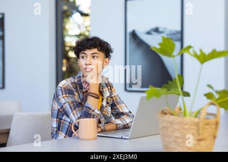 Pensandoci bene, adolescente con un computer portatile e una tazza da caffè a casa Foto Stock