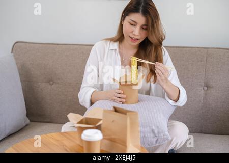 Donna asiatica con cibo da asporto e bevande a casa. Consumo eatingÂ consegna a domicilio di cibo. gusta una deliziosa consegna da asporto Foto Stock