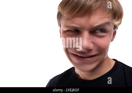 Un ragazzo adolescente divertente con i capelli biondi fa una brutta piaga Foto Stock