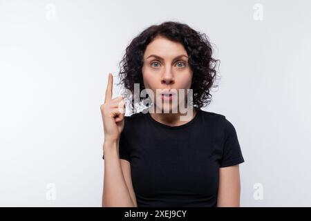 Donna europea riccia adulta che indossa una t-shirt nera ispirata a un'idea Foto Stock