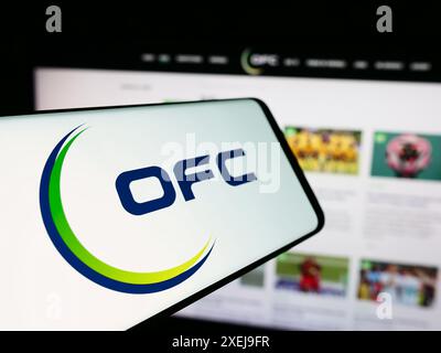 Cellulare con logo dell'associazione Oceania Football Confederation (OFC) davanti al sito web. Mettere a fuoco la parte centrale sinistra del display del telefono. Foto Stock