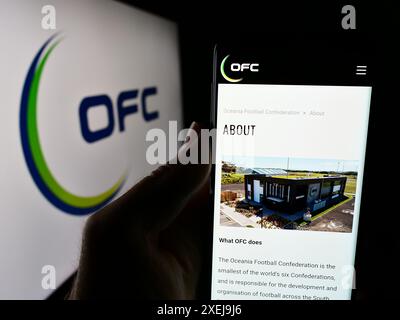 Persona che possiede uno smartphone con il sito web dell'associazione Oceania Football Confederation (OFC) davanti al logo. Messa a fuoco al centro del display del telefono. Foto Stock