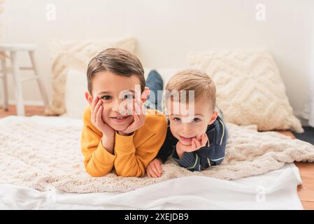 Due fratelli stesi su coperte sulla pancia e sorridono alla macchina fotografica Foto Stock