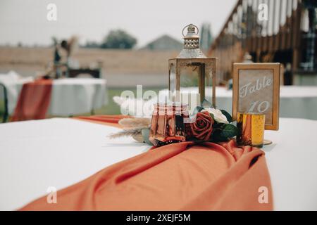 Tavolo per matrimoni all'aperto con lanterna centrale, fiori e. Foto Stock