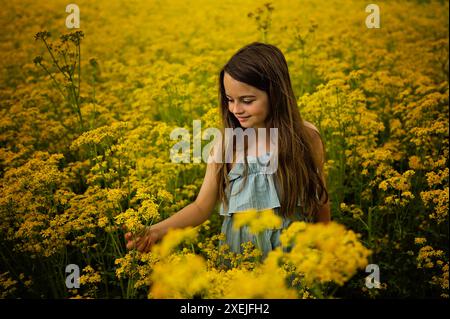 Bella ragazza in piedi nel campo di fiori gialli cielo blu Foto Stock