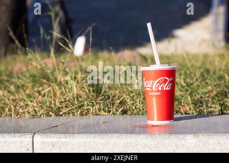 Bielorussia, Minsk - 29 ottobre 2023: Primo piano un bicchiere di Coca Cola sul marciapiede Foto Stock