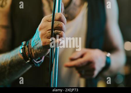 Foto ravvicinata della mano tatuata di un musicista rock maschile irriconoscibile che tiene in mano il supporto del microfono Foto Stock