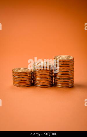 Monete metalliche gialle rotonde piegate sotto forma di colonne su uno sfondo semplice e colorato Foto Stock