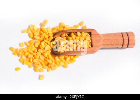 Toor dal o lenticchie gialle divise in un cucchiaio di legno isolato. Ceci spaccati in un sacchetto noto anche come Chana dal, piselli spaccati di Chana gialla, ceci secchi Foto Stock