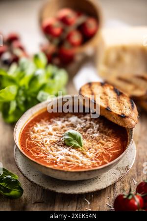 Sana zuppa vegetariana di pomodoro con parmigiano e basilico. Cucina italiana e mediterranea. Foto Stock