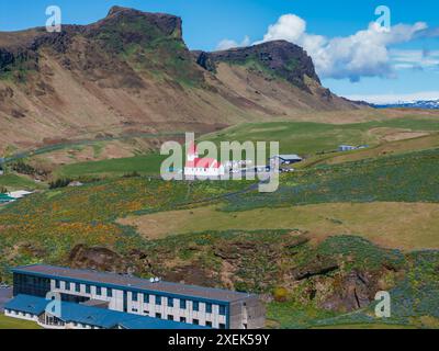 Veduta aerea della Chiesa del tetto Rosso a Vik i Myrdal, Islanda, circondata da Green Hills Foto Stock