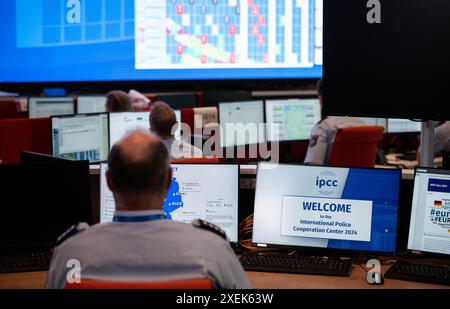 Neuss, Germania. 28 giugno 2024. Un agente di polizia guarda i monitor dell'IPCC. Il Cancelliere federale Olaf Scholz (SPD) e il ministro dell'interno dell'NRW Herbert Reul (CDU) visitano il Centro internazionale di cooperazione di polizia. Al Centro Internazionale di cooperazione di polizia, 300 agenti di polizia del governo federale, degli stati federali e dei 24 paesi partecipanti stanno mettendo in comune informazioni sui campionati europei. Crediti: Fabian Strauch/dpa/Alamy Live News Foto Stock