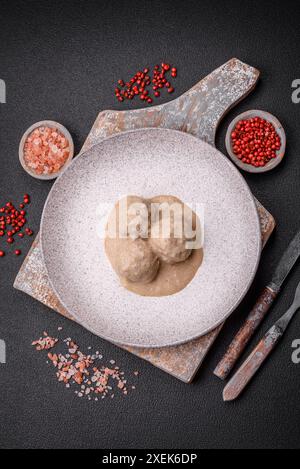 Deliziose polpette di pollo tritato o tacchino con salsa di panna acida con sale e spezie su un piatto di ceramica Foto Stock