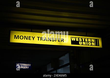 Insegna gialla e nera per il trasferimento di denaro Western Union appesa a un soffitto situata in una zona commerciale di periferia Foto Stock