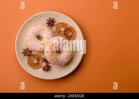 Deliziose ciambelle dolci e luminose con panna su fondo liscio Foto Stock