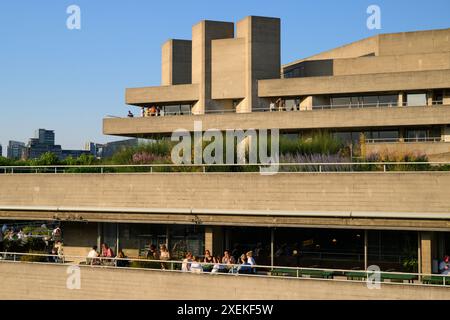 Persone sedute sulle terrazze del Teatro Nazionale godendosi il sole della sera. Il National Theatre fa parte del Southbank Centre. Il teatro Foto Stock