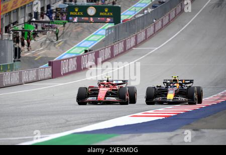 Spielberg, Austria. 28 giugno 2024. Il pilota spagnolo della Ferrari Carlos Sainz (L) e il pilota messicano della Red Bull Racing Sergio Perez gareggiano durante la prima sessione di prove del Gran Premio d'Austria di Formula 1 a Spielberg, in Austria, il 28 giugno 2024. Credito: He Canling/Xinhua/Alamy Live News Foto Stock