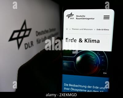 Persona che detiene un cellulare con pagina web di Deutsches Zentrum für Luft- und Raumfahrt e.V. (DLR) davanti al logo. Messa a fuoco al centro del display del telefono. Foto Stock