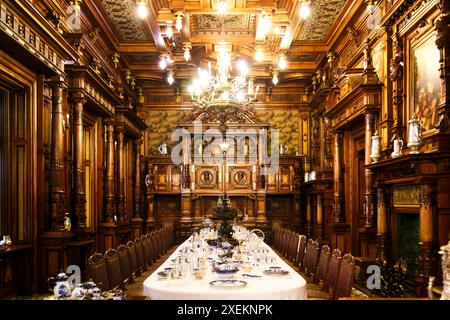 Sinaia, Romania - 26 agosto 2022: Sala da pranzo con tavolo servito ricoperto di tovaglie bianche all'interno del castello di Peles. Il ricco interno del Peles Foto Stock