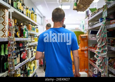 Nago Torbole, Lago di Garda, Italia - 27 giugno 2024: Un negozio di villeggiatura al supermercato Coop di Torbole, Italia, e gode della vasta selezione di cibi e bevande regionali **** Ein Urlauber kauft im Coop Supermarkt di Torbole, Italien, ein und genießt die breite Auswahl an regionalen Lebensmitteln und Getränken Foto Stock