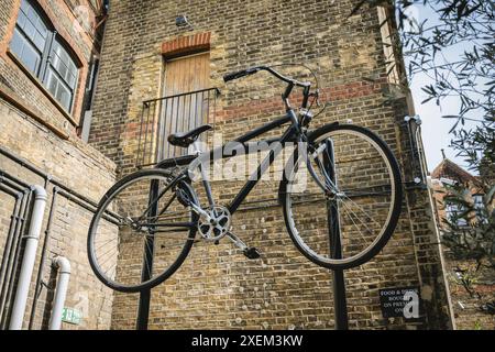 Bicicletta appesa su un rack con un edificio in mattoni sullo sfondo, Borough Market, London Bridge, Londra, Regno Unito; Londra, Inghilterra Foto Stock