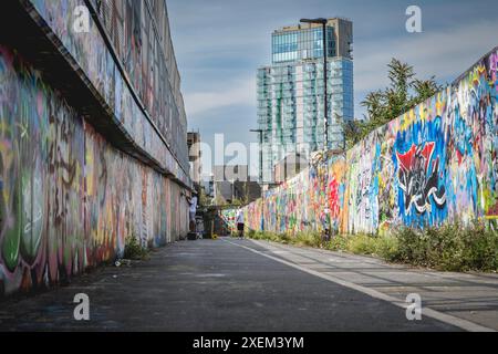 Gli artisti dipingono Street art su un muro lungo Brick Lane, East London, London, UK; Londra, Inghilterra Foto Stock