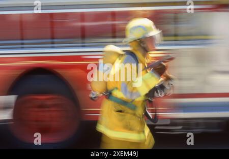 Un vigile del fuoco in piena affluenza sta trasportando un'ascia in un sito di vigili del fuoco, USA 1993 Foto Stock