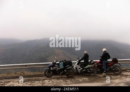 I turisti in viaggio in moto apprezzeranno le vaste vedute da una strada, con una fitta copertura di nuvole che oscurano le vette delle montagne, Yen Bai, Vietnam Foto Stock